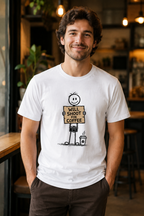 A man wearing a white graphic t-shirt with a cartoon stick figure holding a sign that reads 'WILL SHOOT OR COFFEE'. The background is a blurred cafe interior with warm lighting.